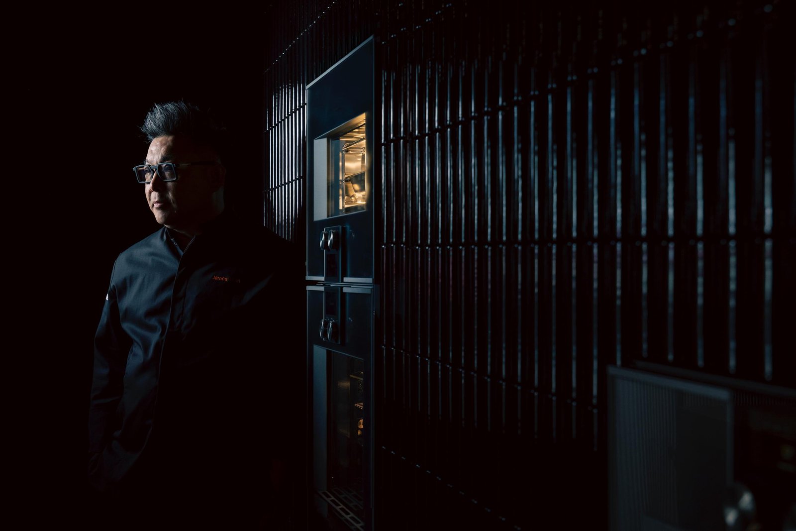 James Won in profile beside an illuminated Gaggenau 400 series combi oven at Inspiration Haus — a cinematic, low-light atelier portrait.