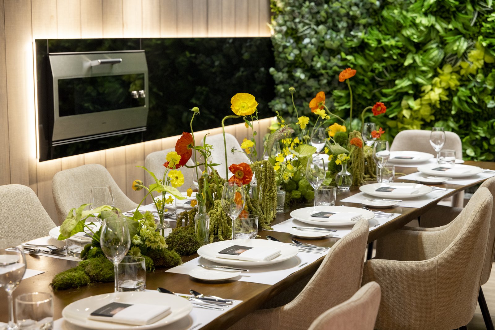 Dining room set for service with the Gaggenau EB333 90cm Professional-grade oven on a timber-clad feature wall, fresh poppies, vertical garden, and premium tableware.