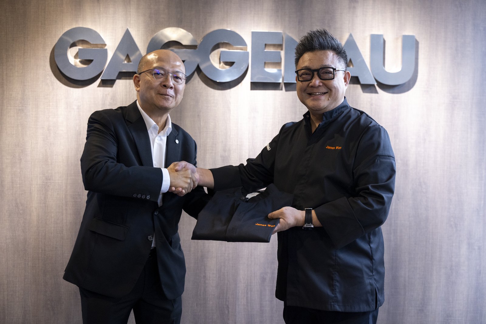 Gary Teh, CEO of BSH Home Appliances, in front of the GAGGENAU sign at Inspiration Haus presenting the GAGGENAU-branded jacket to James Won at the investiture as Malaysia's first Gaggenau Culinary Partner and Ambassador.