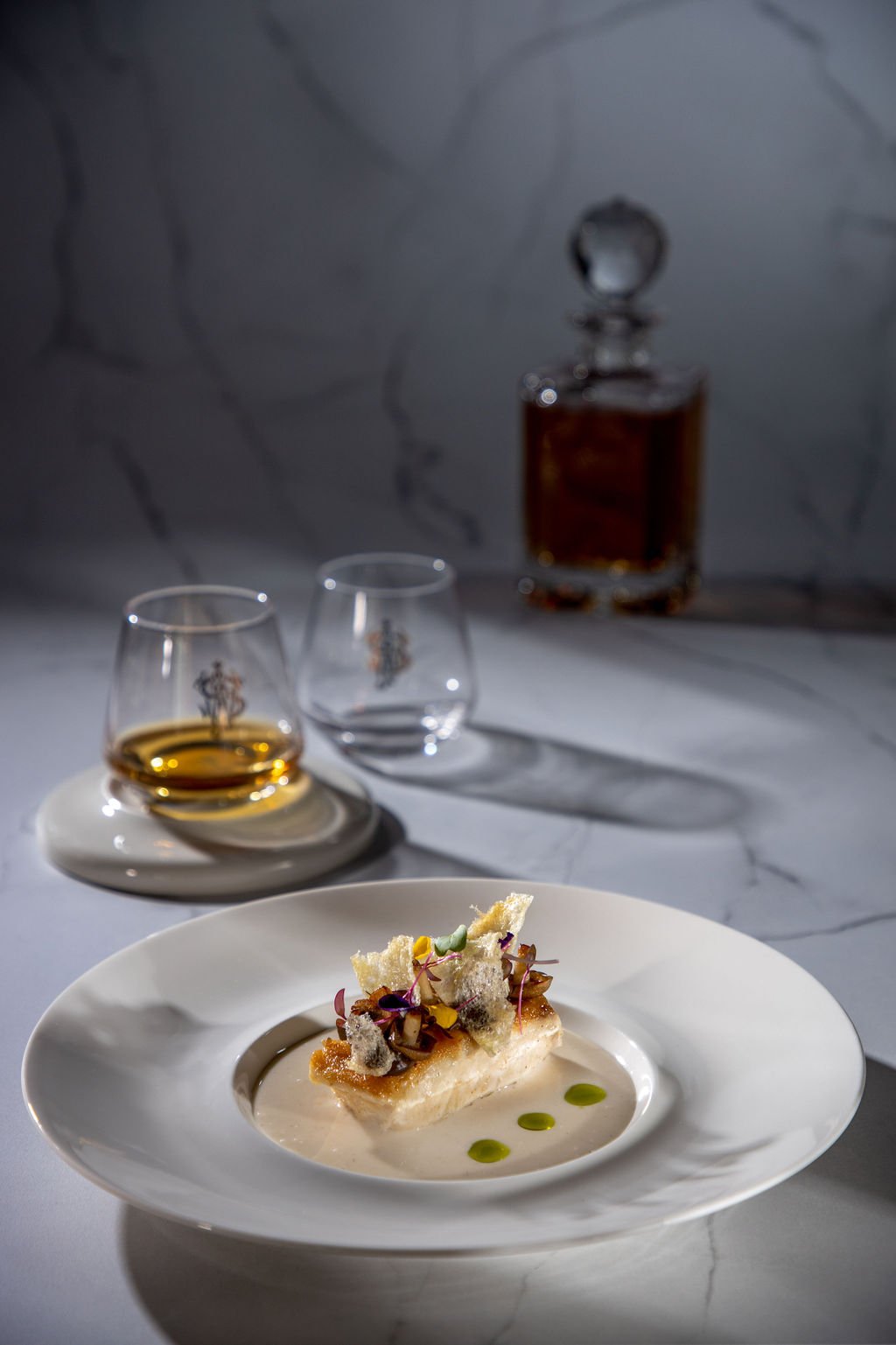 Discover Rarity main — fish meunière with truffles, Bario wine sauce, charred leeks; Johnnie Walker decanter and tasting glasses behind.