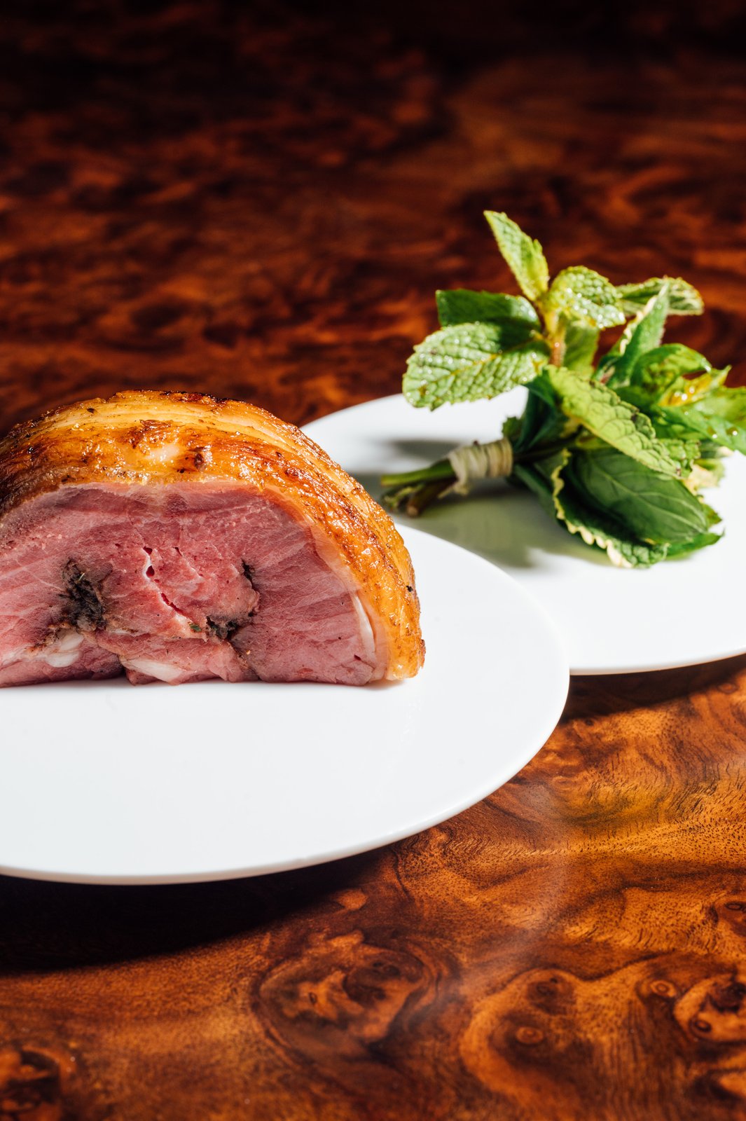 A beef course wrapped en croute, sliced to show the rosy centre, served with a bundle of fresh mint.