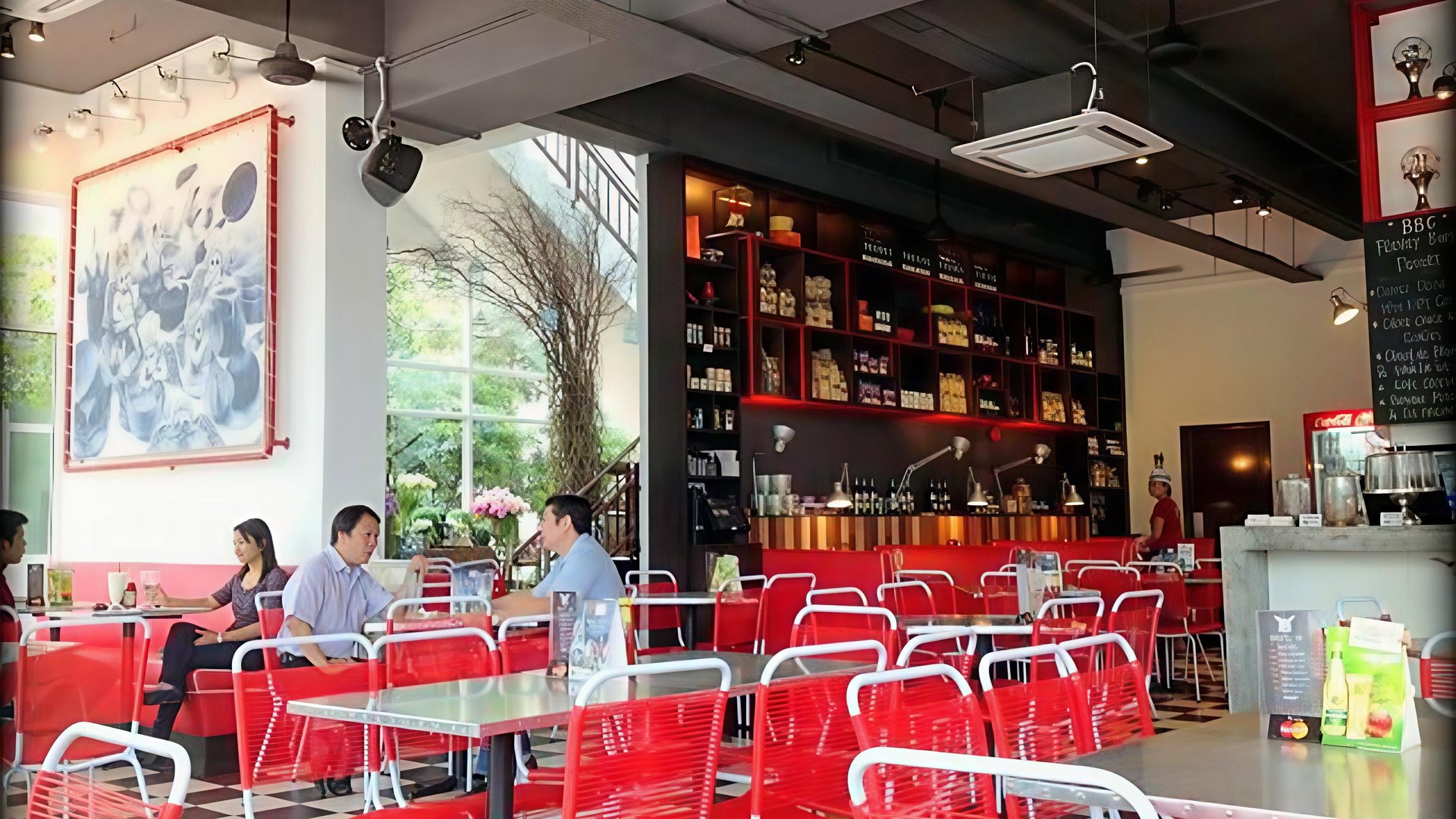 The BadBoyCooks Diner room at Oasis Square — iconic red wire chairs, marble counter, mural artwork, blackboard specials, mid-morning service.