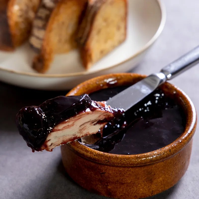 Chicken liver parfait sealed with port-wine jelly in a stoneware ramekin, with charred sourdough behind.
